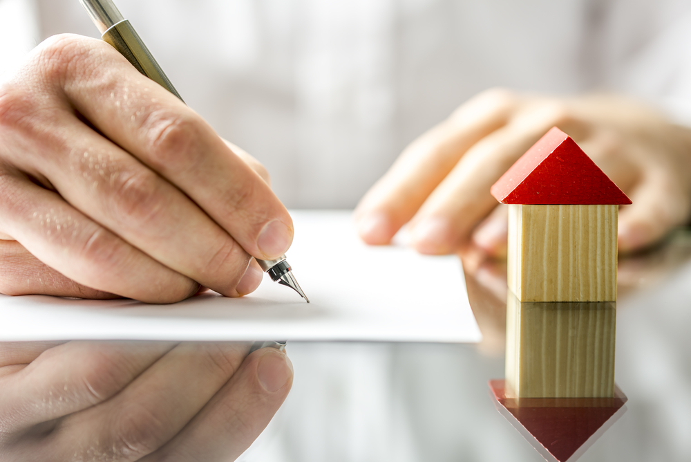 someone signing a document to denote a story about home insurance